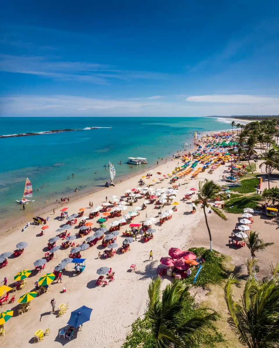 Vista aérea da Praia do Francês com guarda-sóis coloridos e mar turquesa